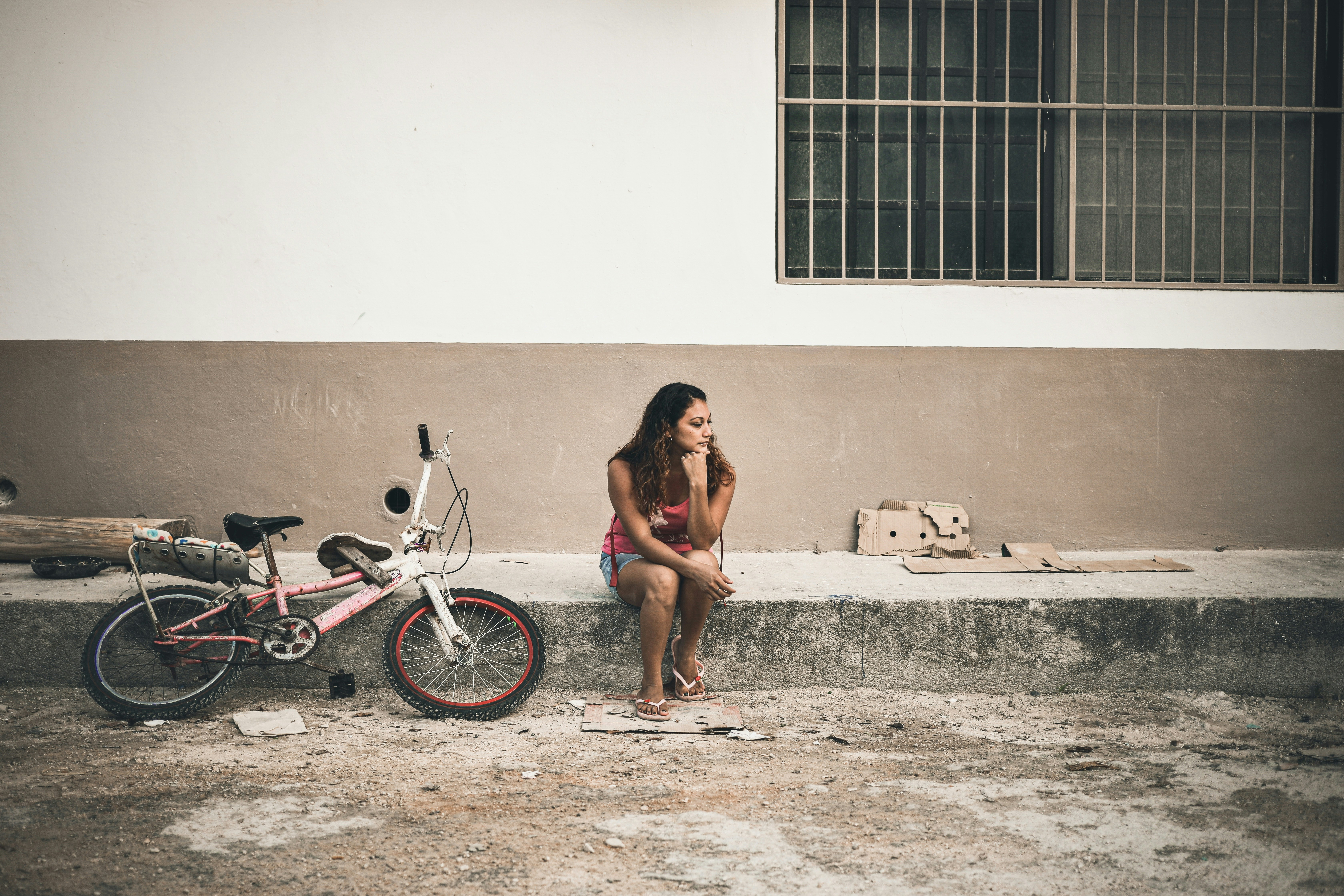 a woman sitting next to a bike on the side of a road